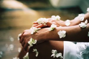 Woman with flower petals over hands, wrists, and legs. Picture is symbolic of the beauty inside and outside of each one of us.